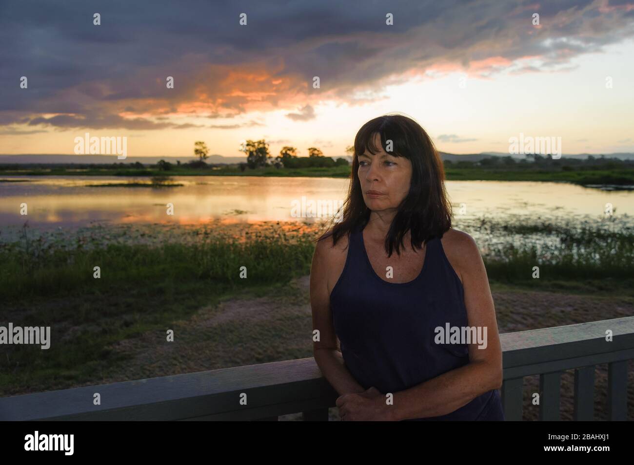 Female tourist, at sunset, leaning on viewing platform rail, at the St. Lawrence Wetlands, near Mackay, Queensland, Australia. Stock Photo