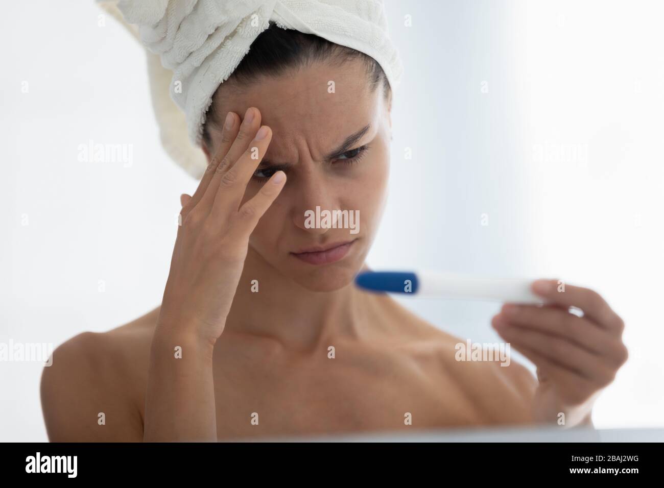 Closeup frustrated by negative pregnancy test result woman in bathroom Stock Photo