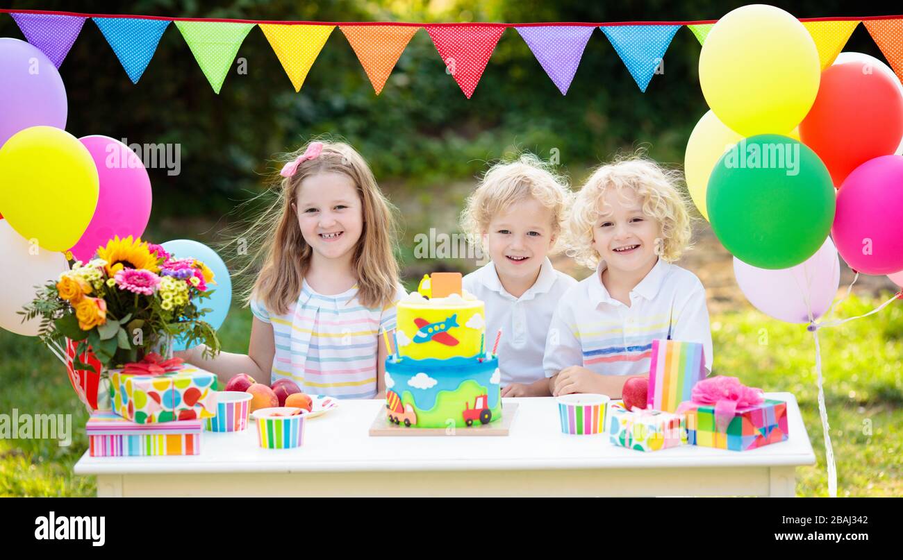 Children blow candles on birthday cake. Kids party decoration and food. Boy and girl celebrating birthday of little brother. Transport and car kid eve Stock Photo