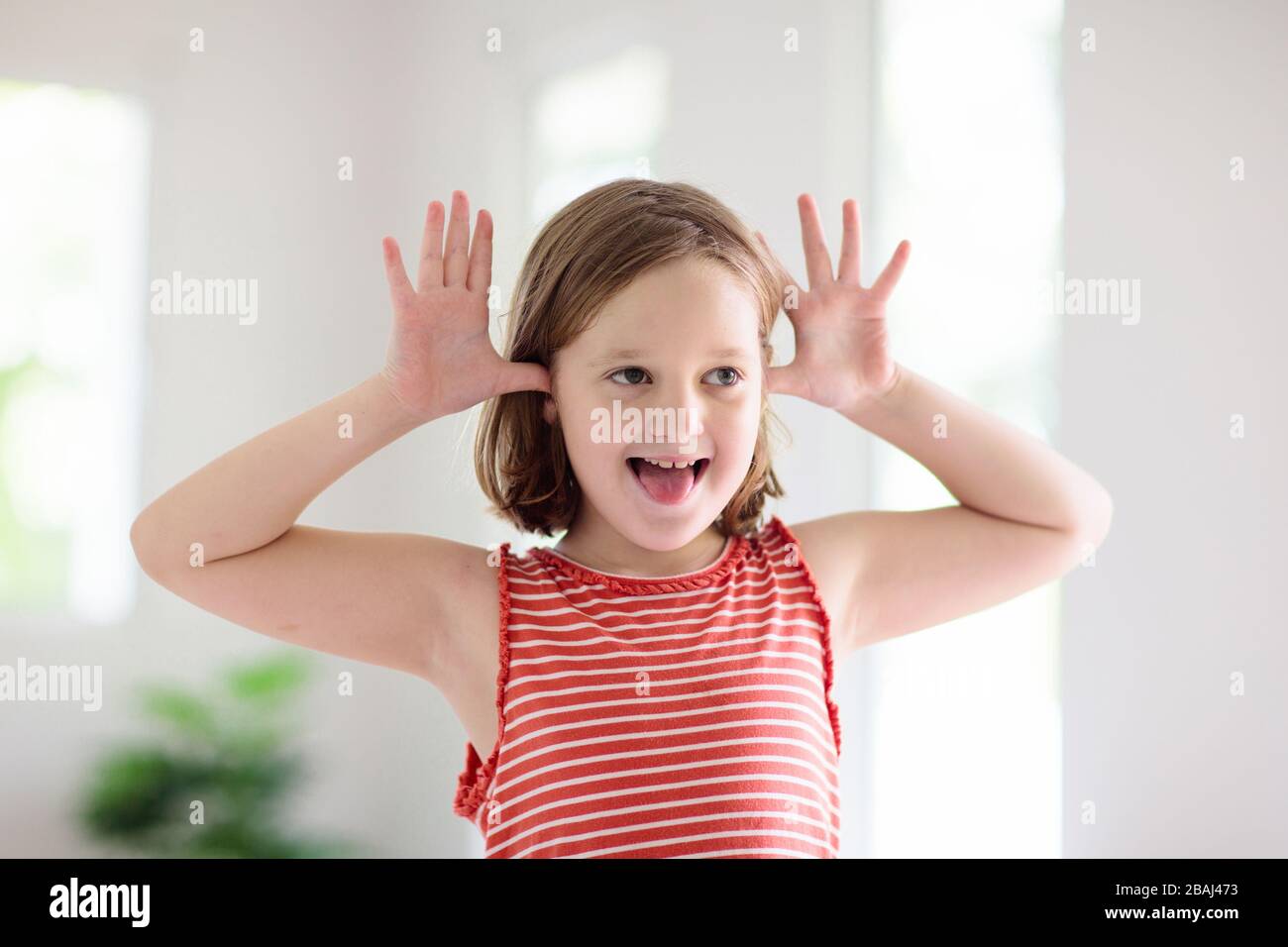 Child making funny face. Kid teasing and laughing. Silly little girl