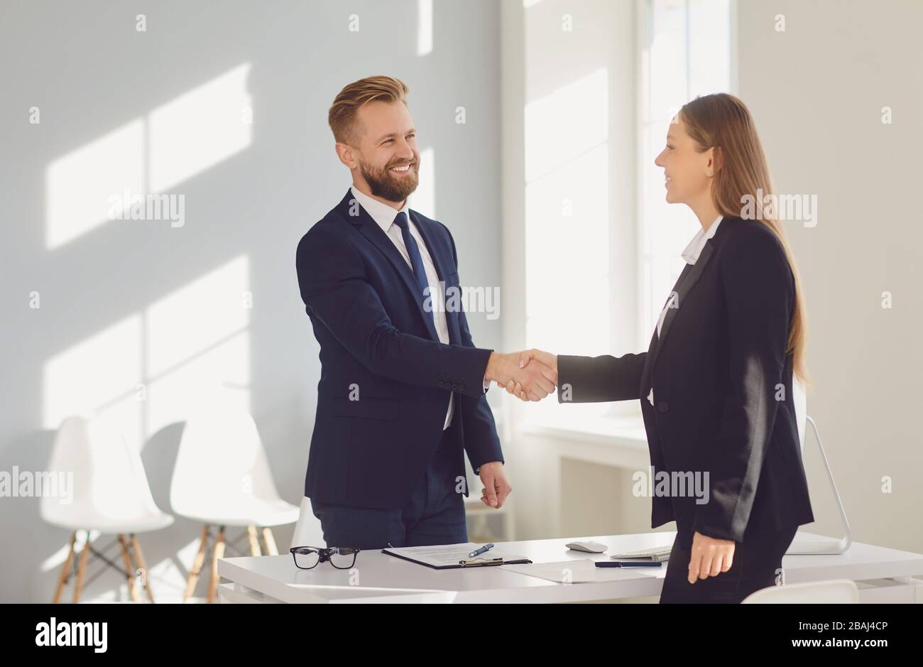 Successful office interview. The conclusion of the contract. Businessman and businesswoman handshake at the table after meeting. Stock Photo