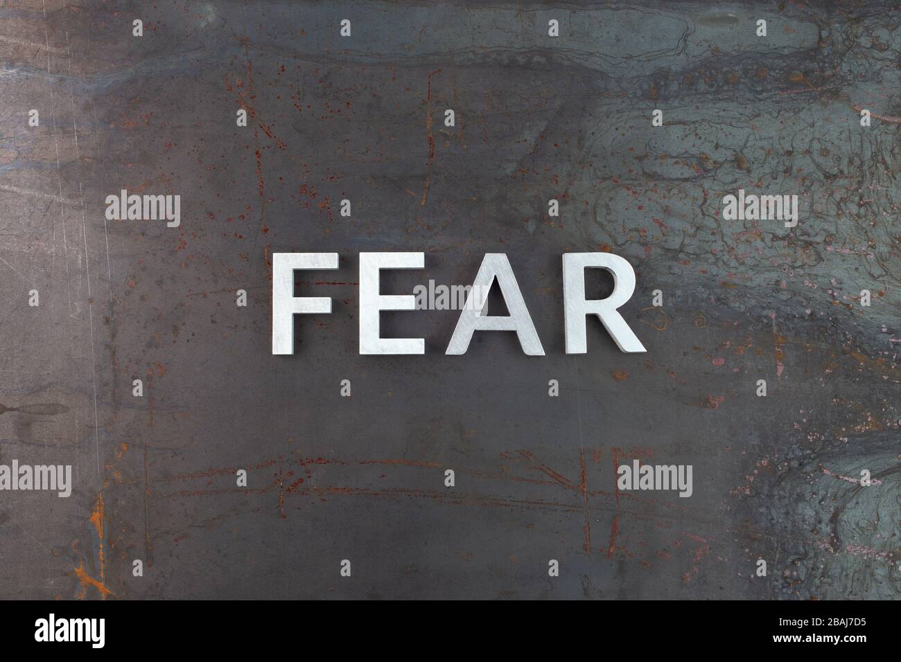 the word fear laid with silver letters on raw rusted steel sheet surface in flat lay composition Stock Photo