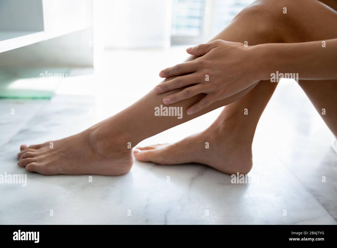 Female touches smooth silky legs enjoy skin after epilation procedure Stock Photo
