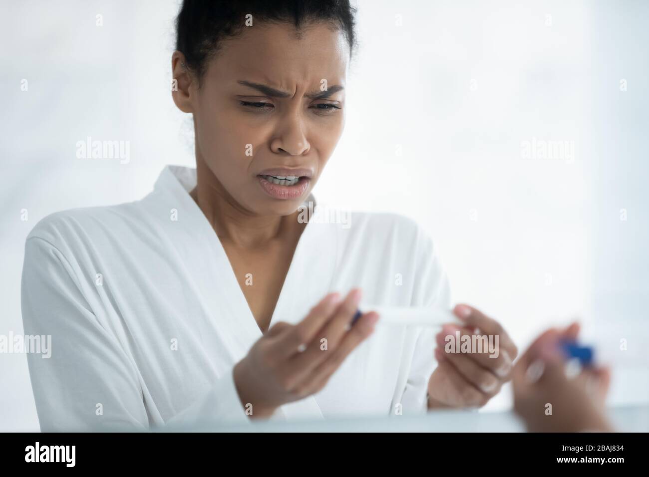 African woman see positive result on pregnancy test feels shocked Stock Photo