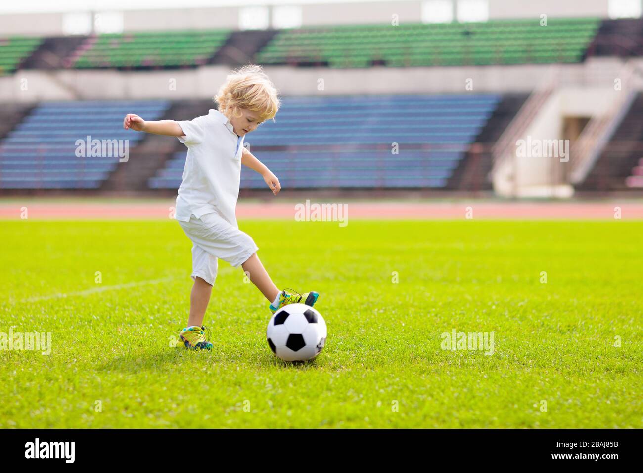 Kids play football on outdoor stadium field. Children score a goal