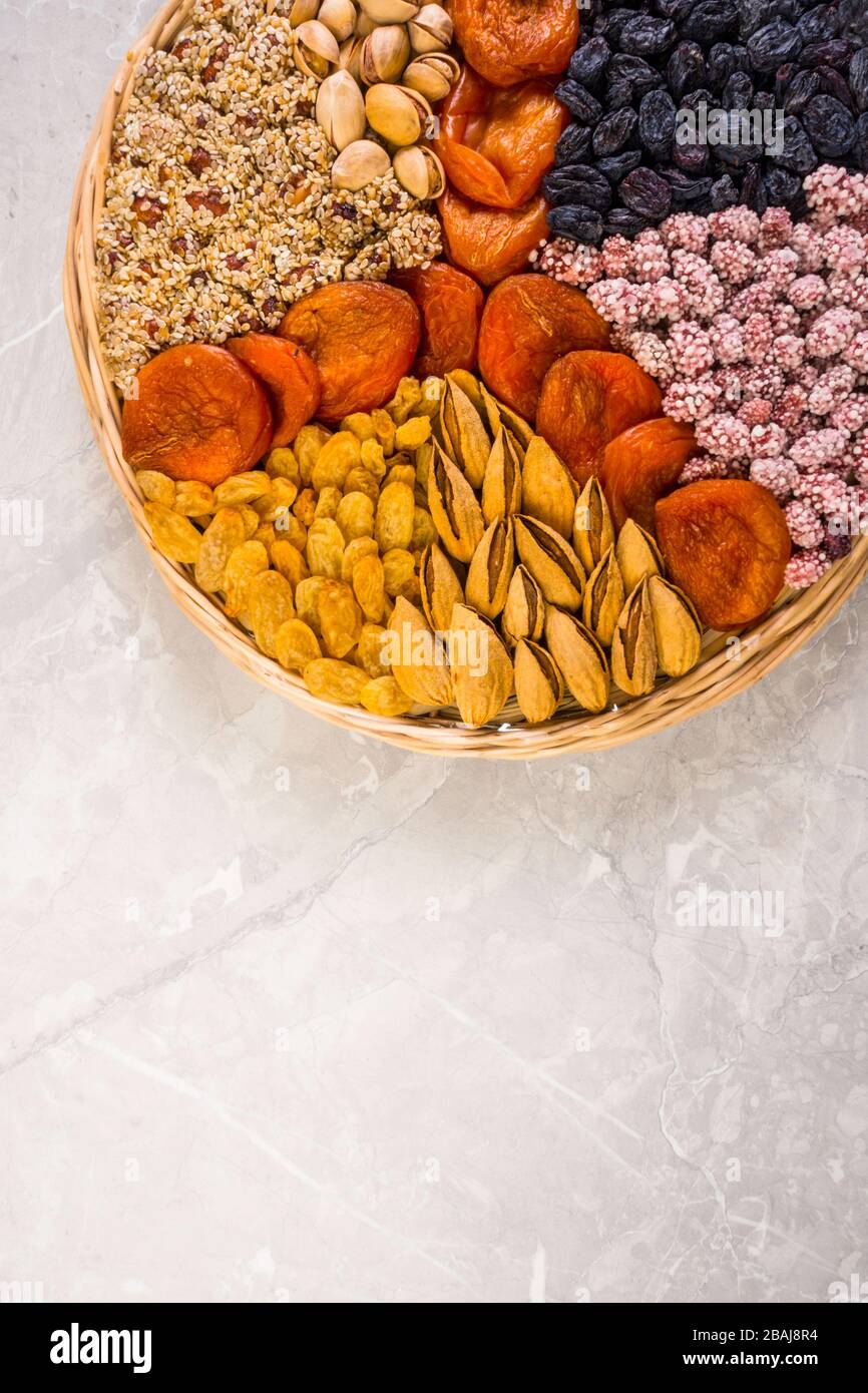 Wooden plate with assorted nuts, apricots, raisins, sesame in round