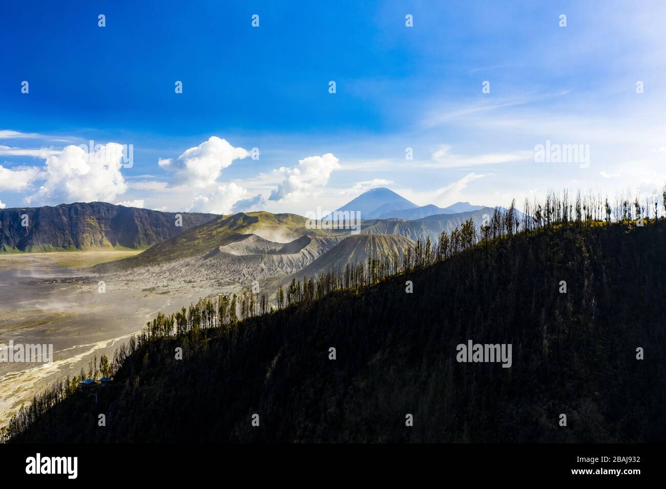 View from above, stunning aerial view of the Mount Bromo crater in the background and a silhouette of an hill in the foreground. Stock Photo