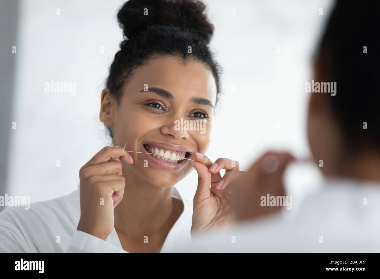 Beautiful smiling african woman holding dental floss cleaning teeth Stock Photo