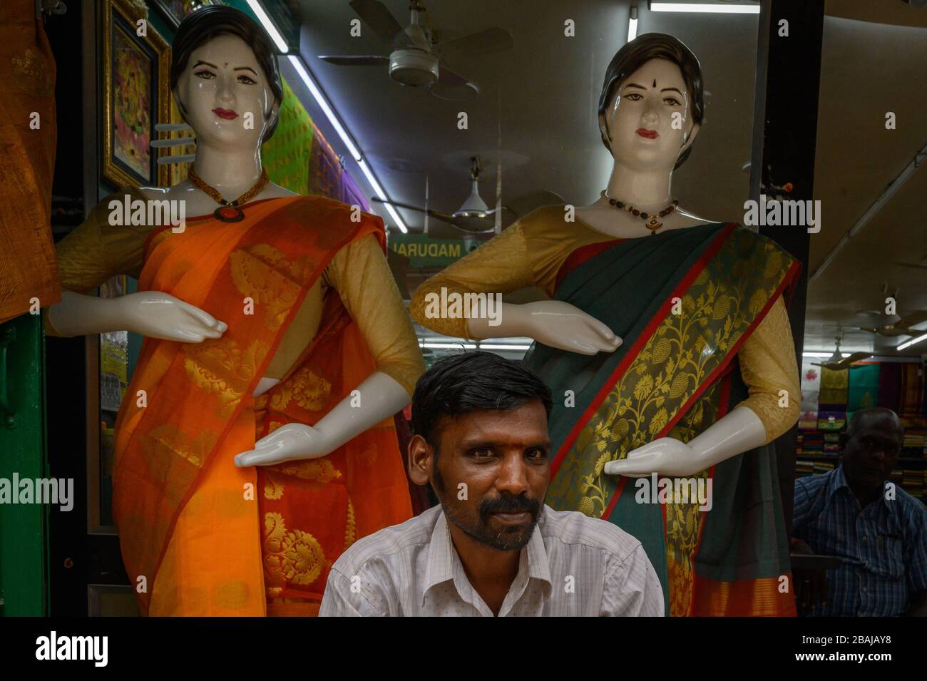 Portrait of a man under two mannequins in a shop window, Madurai, India Stock Photo
