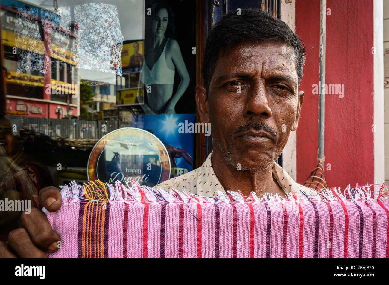 Portrait of a street vendor holding up some cloth, Madurai, India Stock Photo