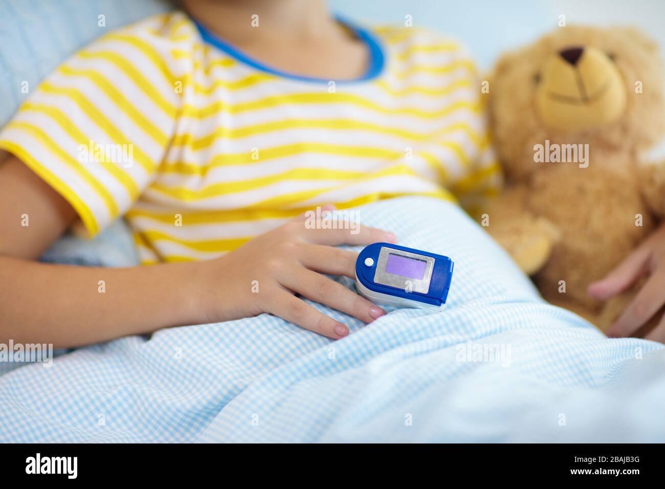 Sick little boy with pulse oximeter on his finger. Asthma treatment. Ill child lying in bed