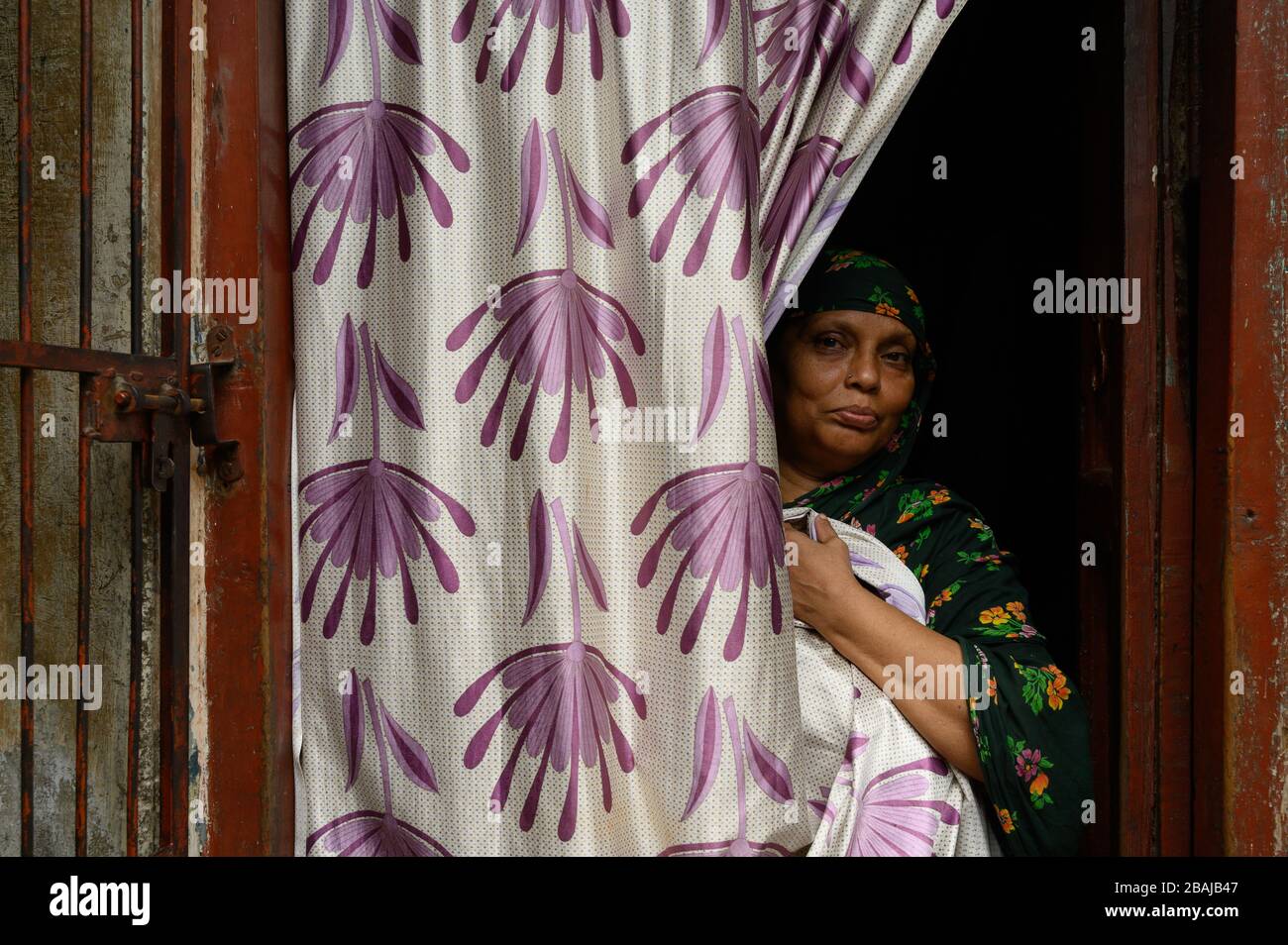 Portrait of a woman behind the curtains in front of her home, Madurai, India Stock Photo