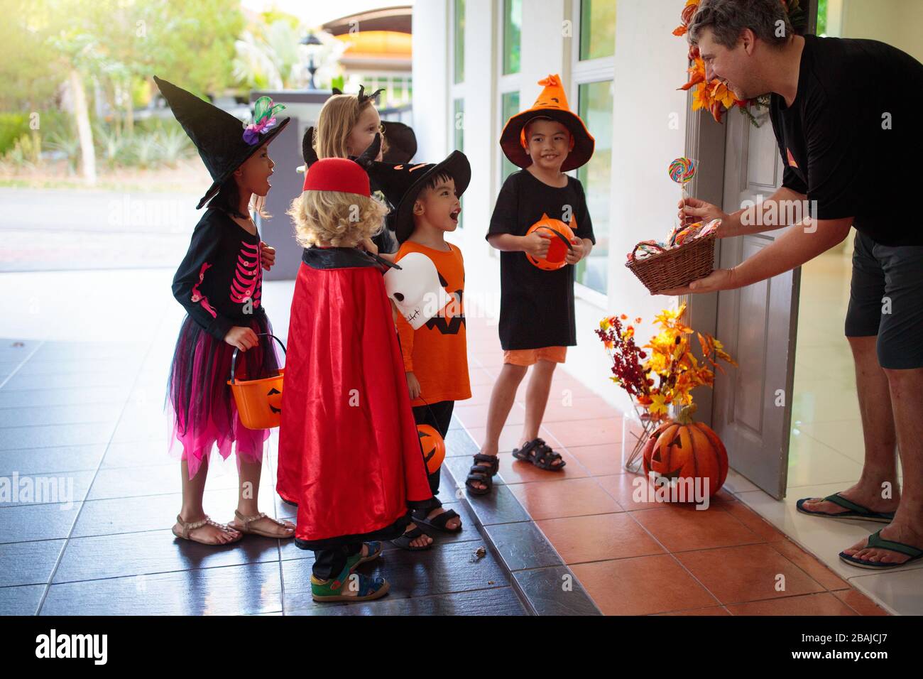 Kids trick or treat on Halloween night. Mixed race Asian and Caucasian  children at decorated house door. Boy and girl in witch and vampire costume  and Stock Photo - Alamy