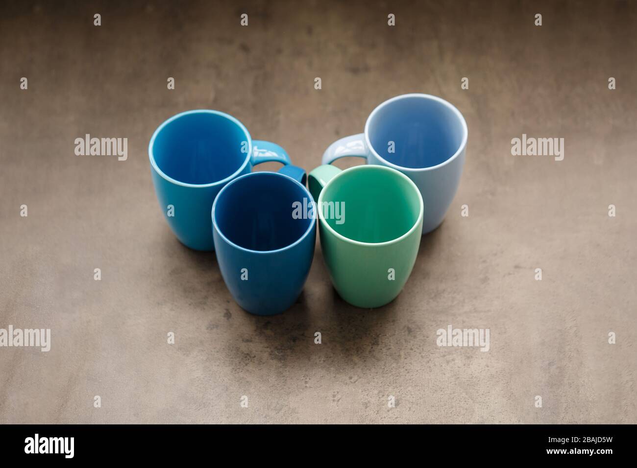 four tea mugs of different colors on a gray background Stock Photo