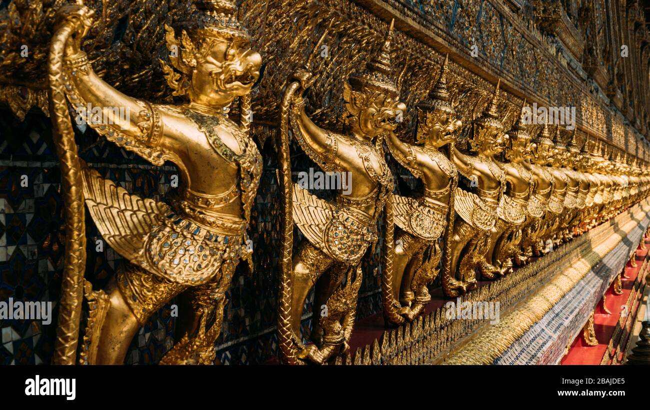 Line of ornate, golden garuda statues hanging on wall of The Emerald Buddha temple, Wat Phra Kaew, Grand Palace, Bangkok, Thailand. Stock Photo