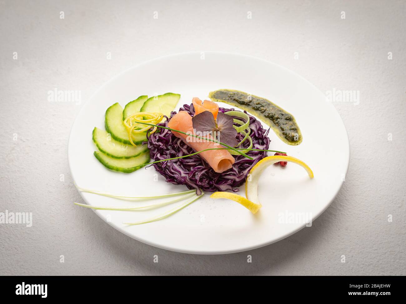 Plate of fresh smoked salmon on fresh vegetables on a white plate, with bright colors and a white background Stock Photo