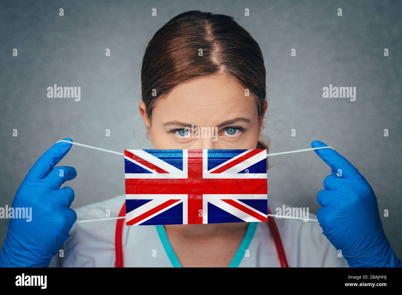 Coronavirus in United Kingdom, Great Britain, England Female Doctor Portrait hold protect Face surgical medical mask with United Kingdom National Flag Stock Photo
