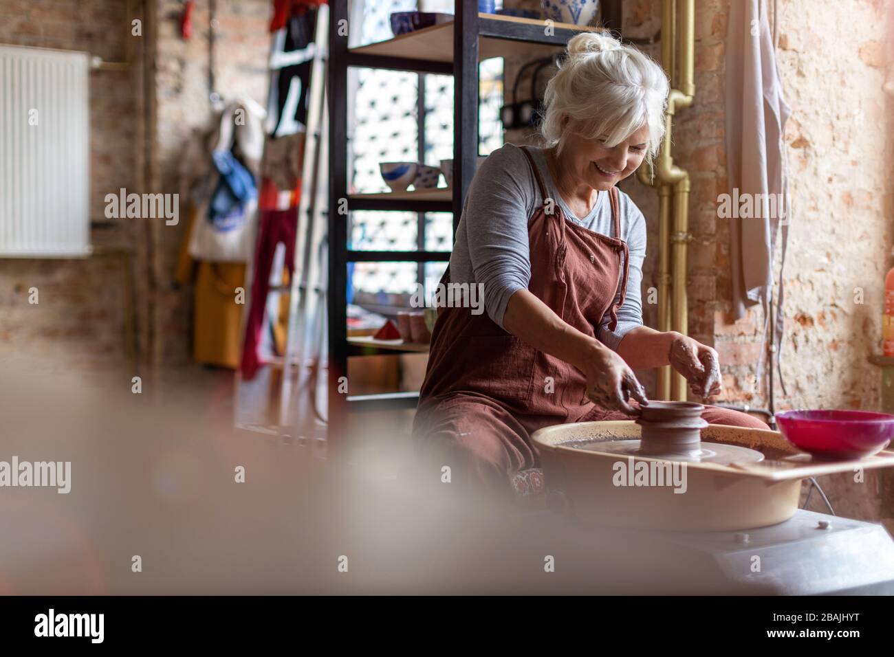 Portrait of senior female pottery artist in her art studio Stock Photo