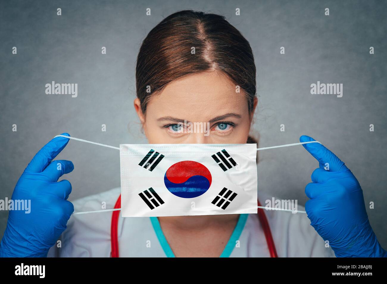 Coronavirus in South Korea Female Doctor Portrait hold protect Face surgical medical mask with South Korea National Flag. Illness, Virus Covid-19 in S Stock Photo