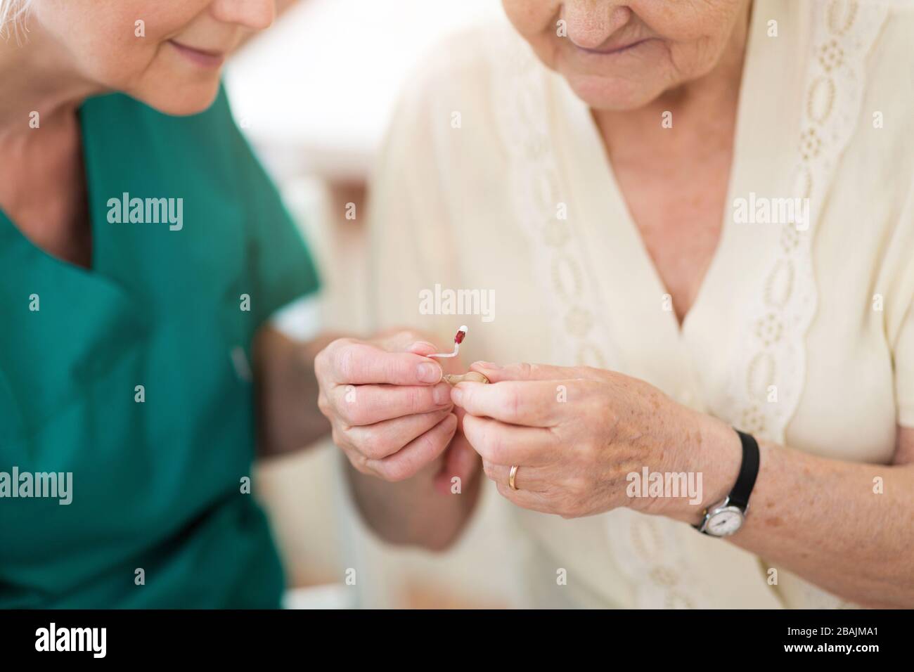 Female doctor applying hearing aid to senior woman's ear Stock Photo
