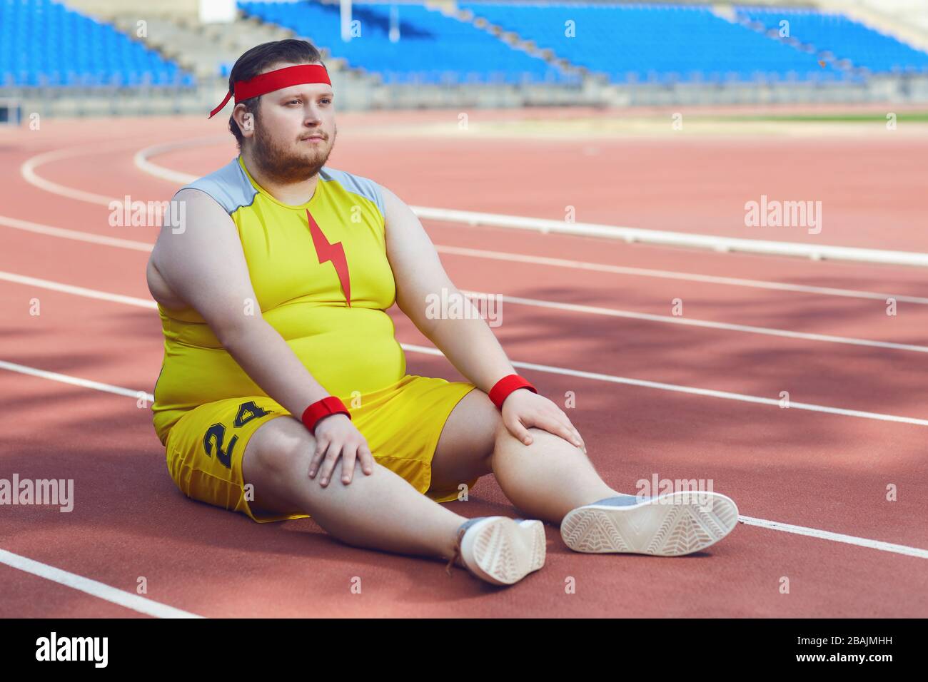 A fat man sits on a track at a stadium Stock Photo