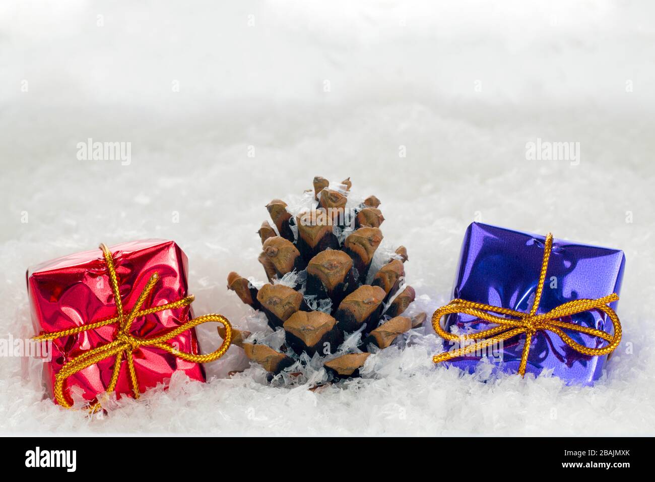 Christmas presents and a fir cone in snow with copy space for adding a custom message Stock Photo