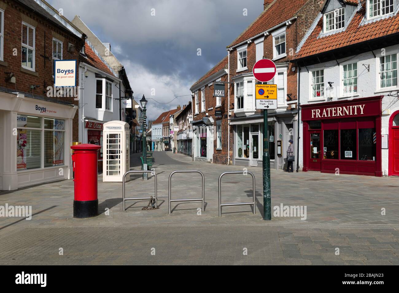 Businesses and shops closed and one solitary pedestrian wearing protective face mask following Corona virus shut-down. Beverley, UK. Stock Photo