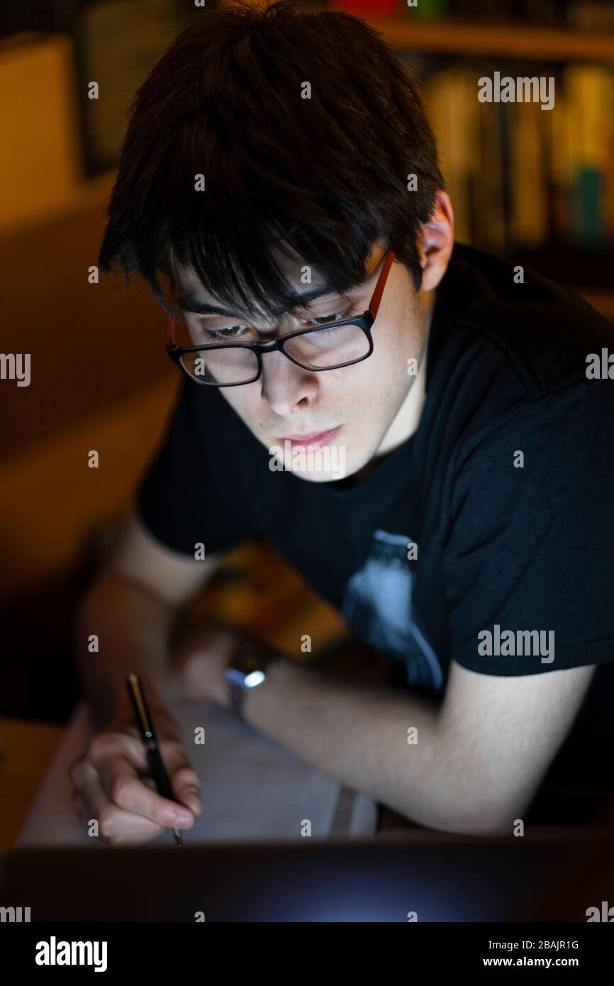 A college student studying in his bedroom Stock Photo