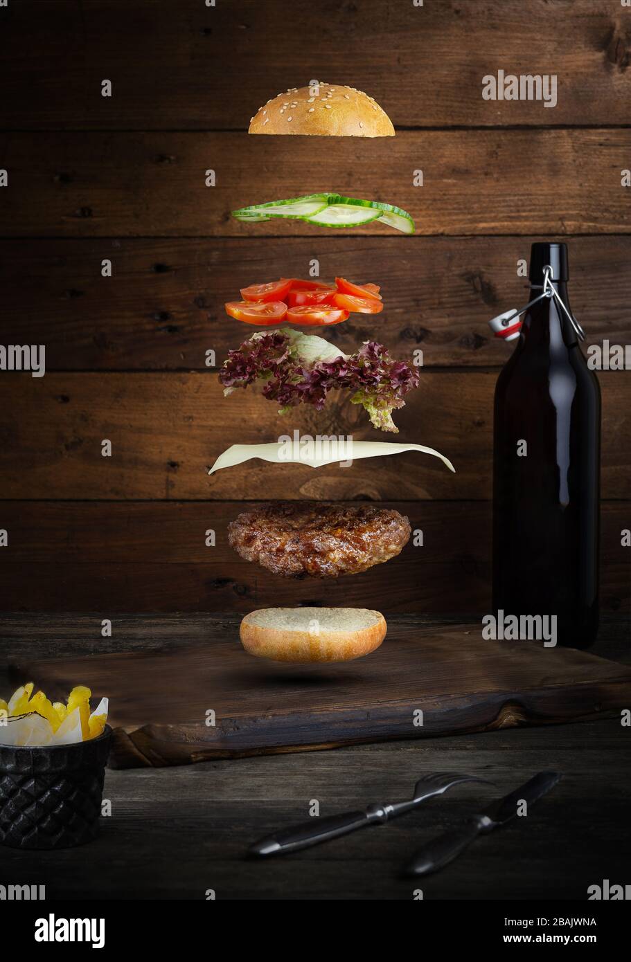 Meat burger with flying ingredients, isolated, with copyspace for text or logo, black background and bright colors Stock Photo