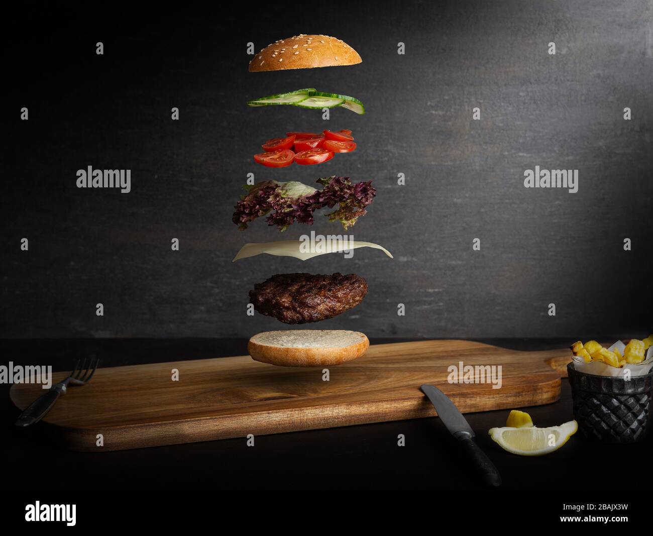 Meat burger with flying ingredients, isolated, with copyspace for text or logo, black background and bright colors Stock Photo