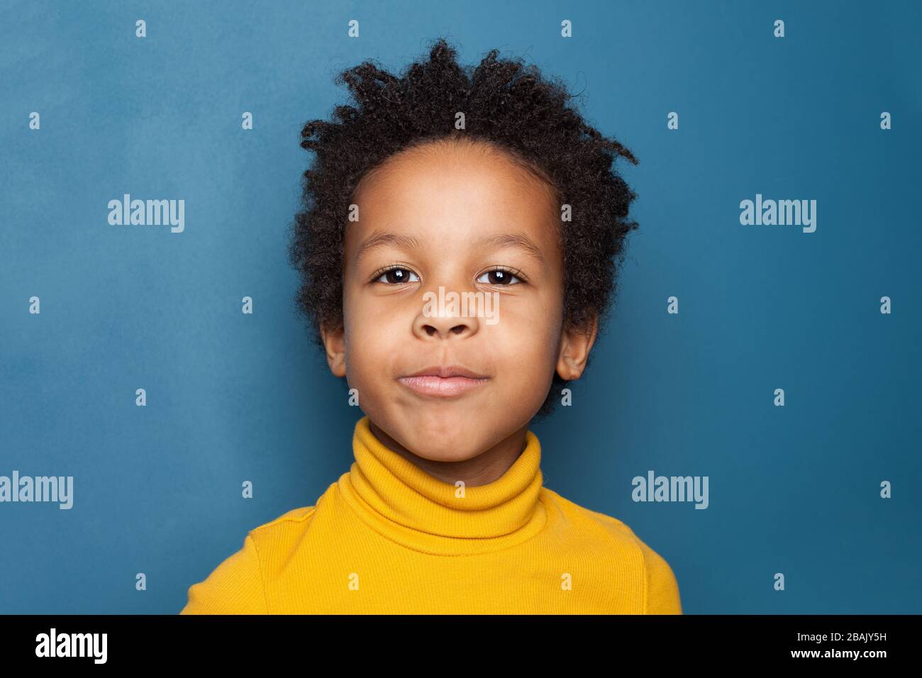 Curious kid portrait. Happy small black child on blue background Stock Photo