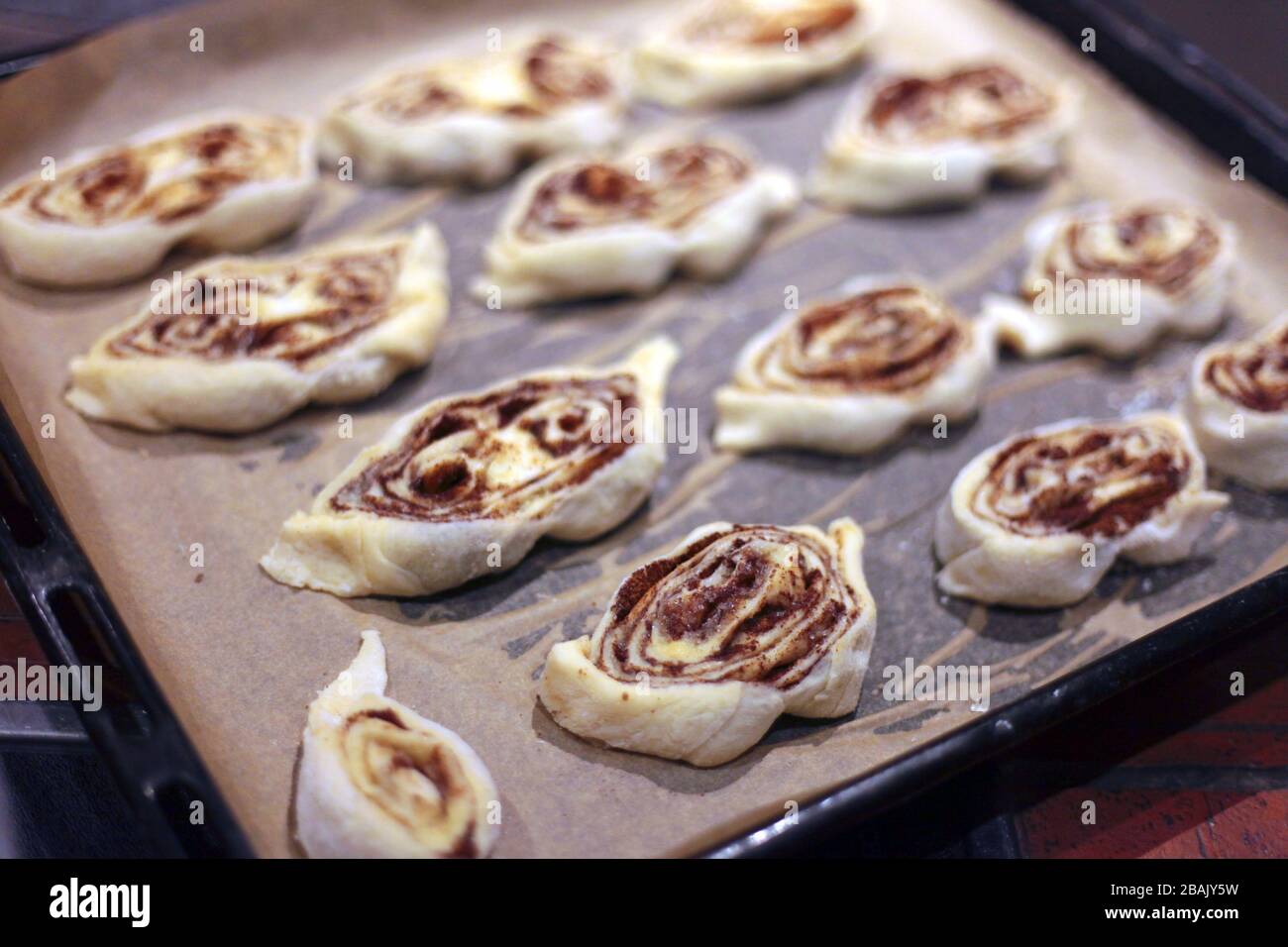 sweet rolls with cinnamon on the tray - backery or cooking at home. A detail of raw cinnamon buns - very shallow depth of field. Stock Photo