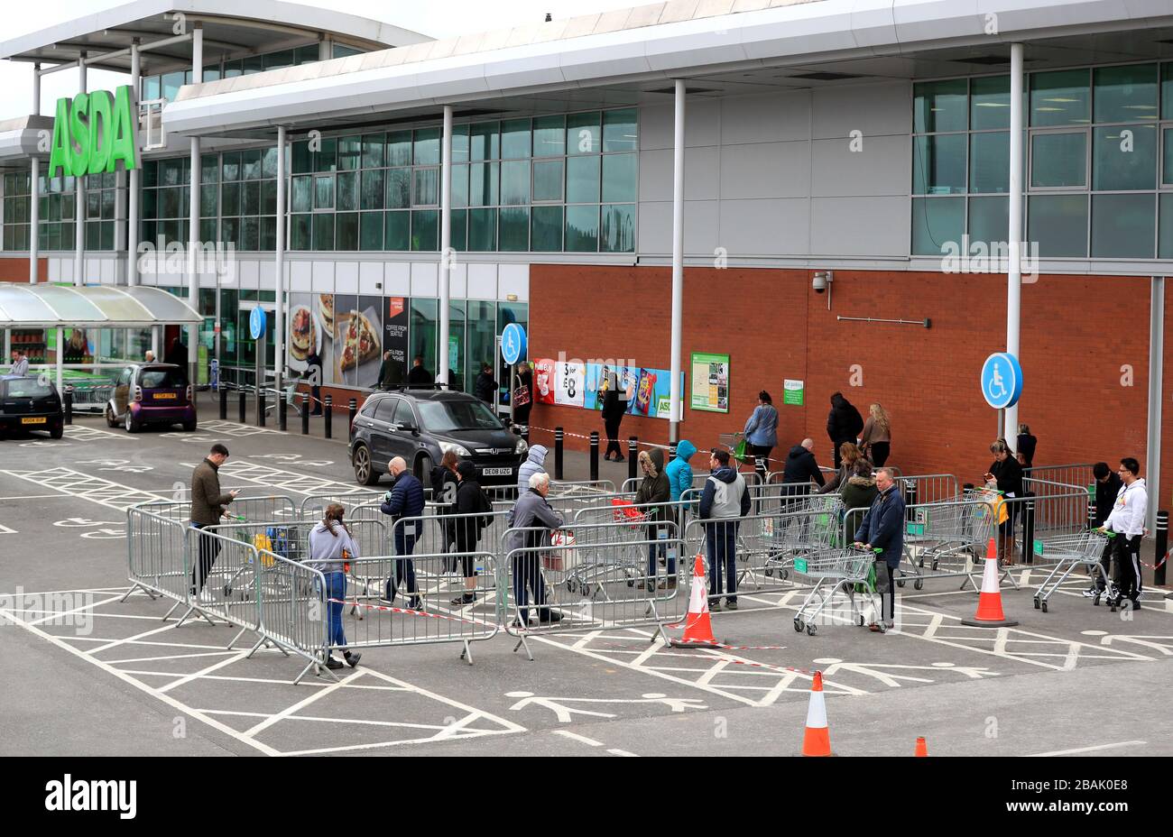 Members of the public observe social distancing measures whilst they queue for Asda in Grantham, Lincolnshire as the UK continues in lockdown to help curb the spread of the coronavirus. Stock Photo