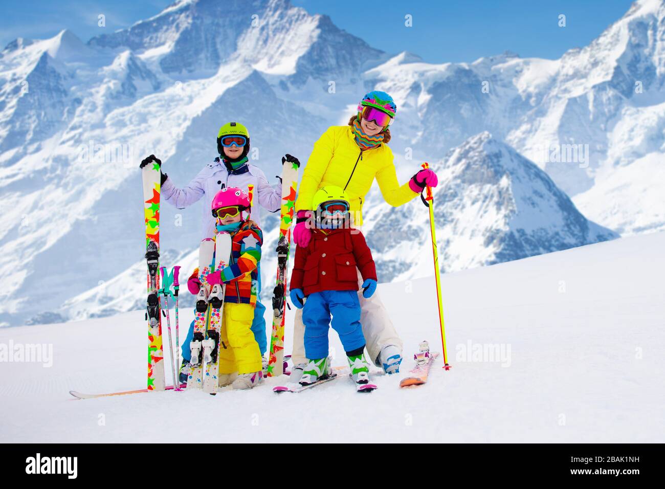 Family ski vacation. Group of skiers in Swiss Alps mountains. Adults and young children, teenager and baby skiing in winter. Parents teach kids alpine Stock Photo