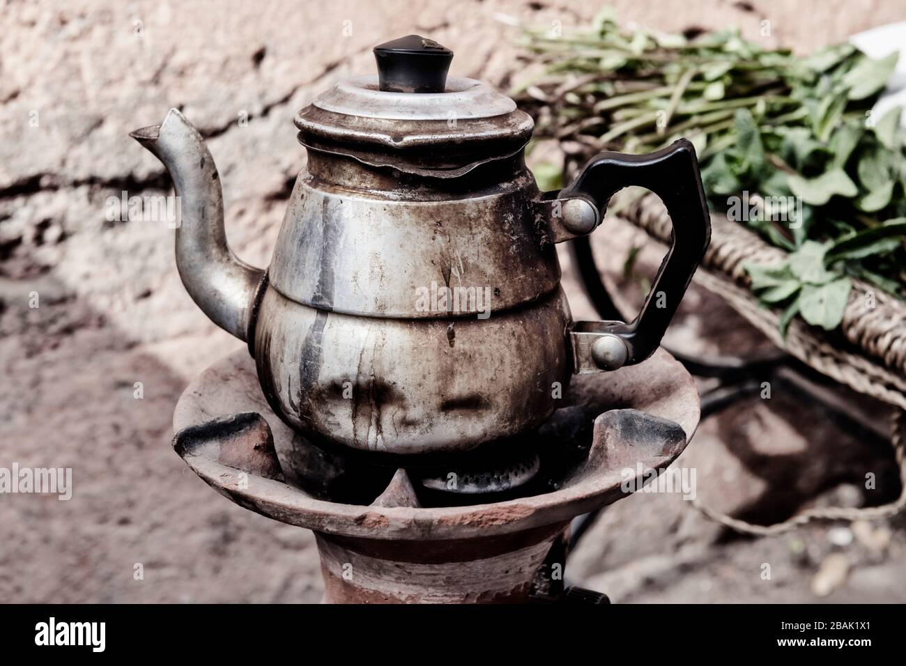 Old rusty teapot with Moroccan mint. Vintage image with film grain. Stock Photo