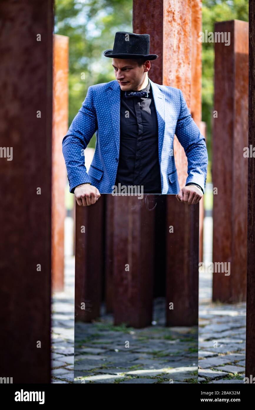 Portrait of a young male athlete in elegant, stylish outfit among raw, rusty iron poles Stock Photo