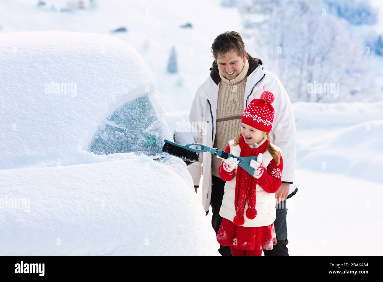 Father and child brushing and shoveling snow off car after storm