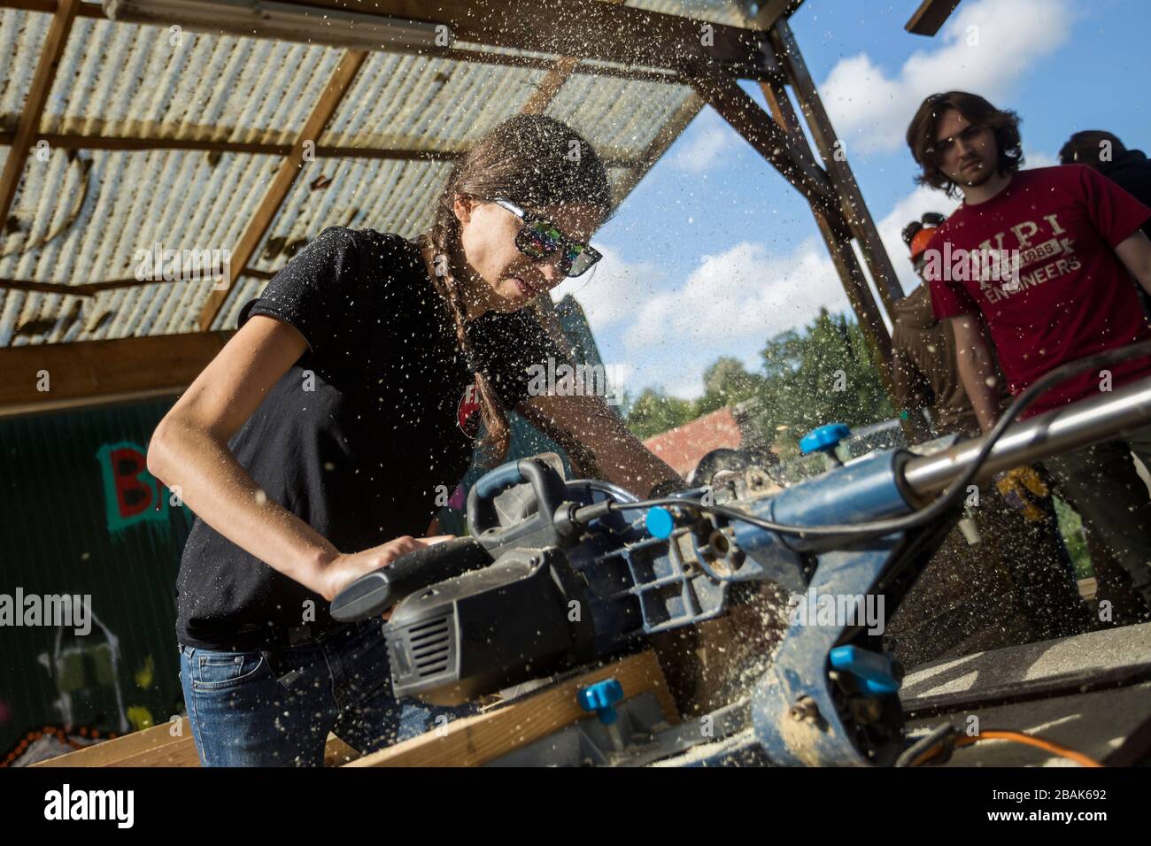 Young woman working hard sawing lumber during a humanitarian mission  a poor roma (gypsy) community in rural Hungary Stock Photo