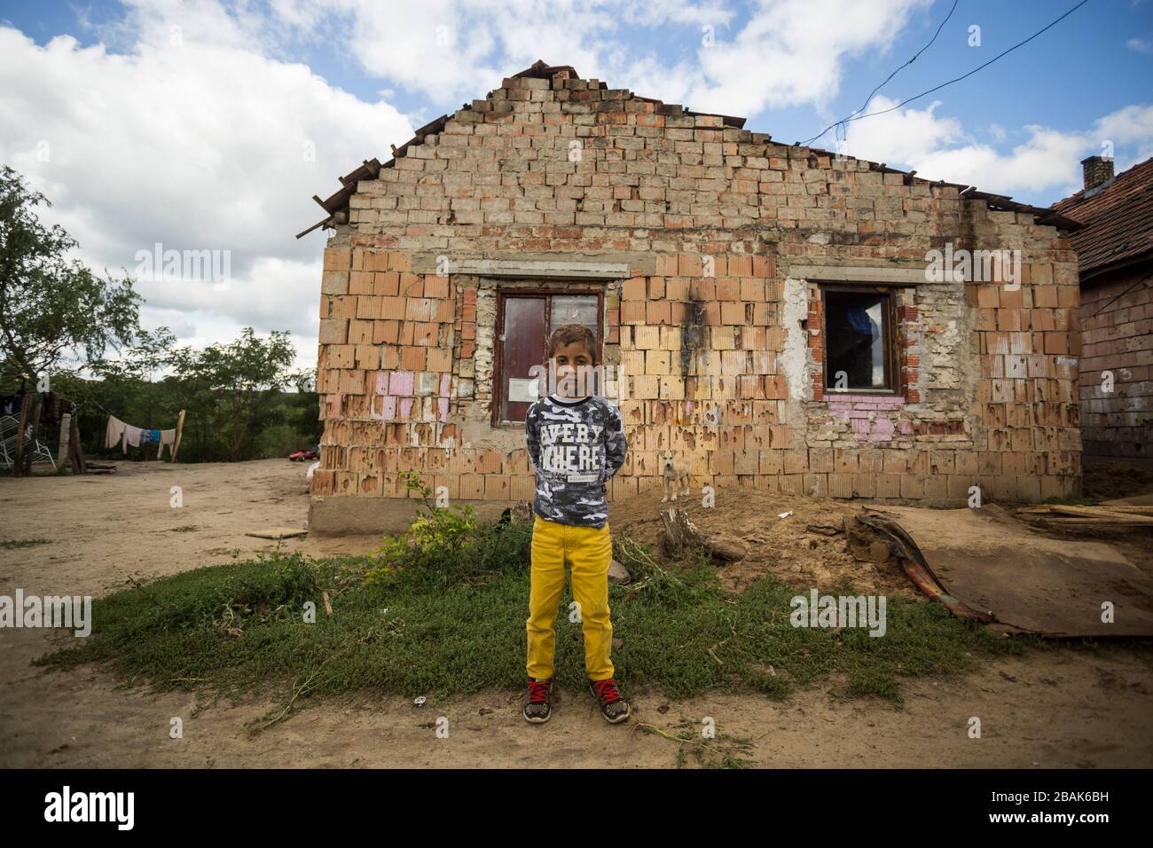 Young gypsy boy in front of a shabby house in  a rural area of Hungary. Stock Photo