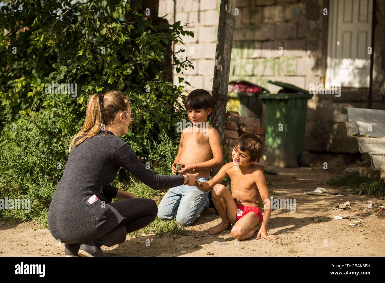 Young humanitarian woman with gypsy children in a poor roma community in rural Hungary Stock Photo