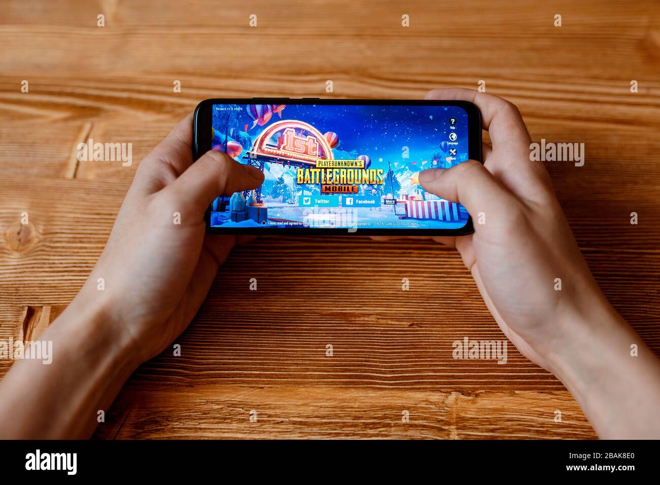 a young guy plays PLAYERUNKNOWN'S BATTLEGROUNDS mobile game on the phone. Smartphone closeup without a face. pubg game. Stock Photo