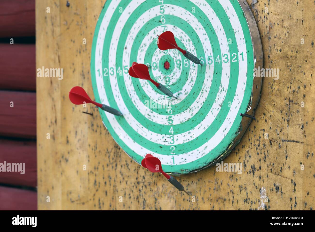 Green and white dartboard with red arrows photographed in Finnish summer cottage. Playing darts is a fun way to spend summer holiday. Relaxing! Stock Photo