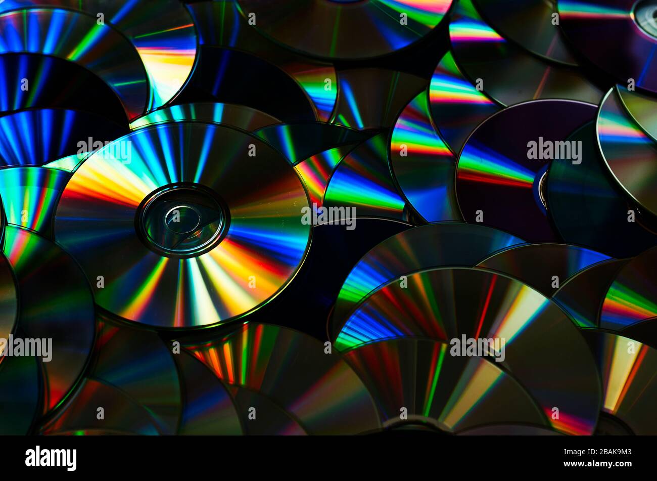 Group of old CD DVD compact optical disk storage medium with dust and scratches. Rainbow spectrum of iridescent colors Stock Photo