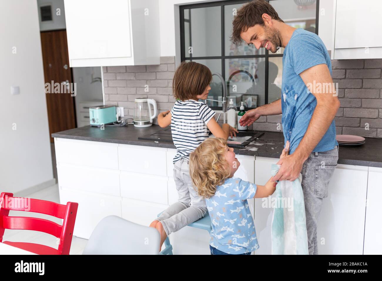 Children helping father in kitchen Stock Photo