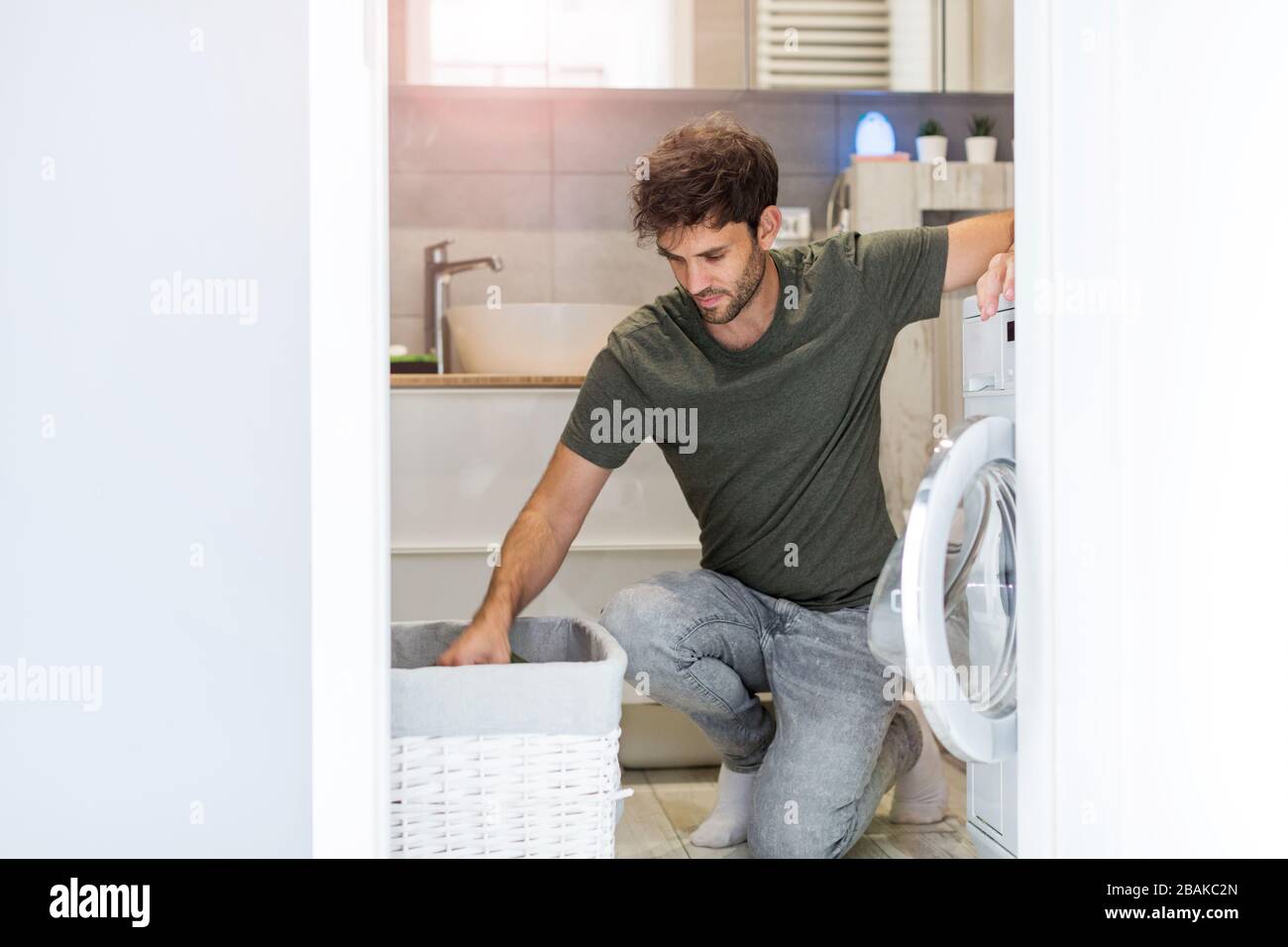 Man Putting his Laundry into a Washing Machine Stock Photo