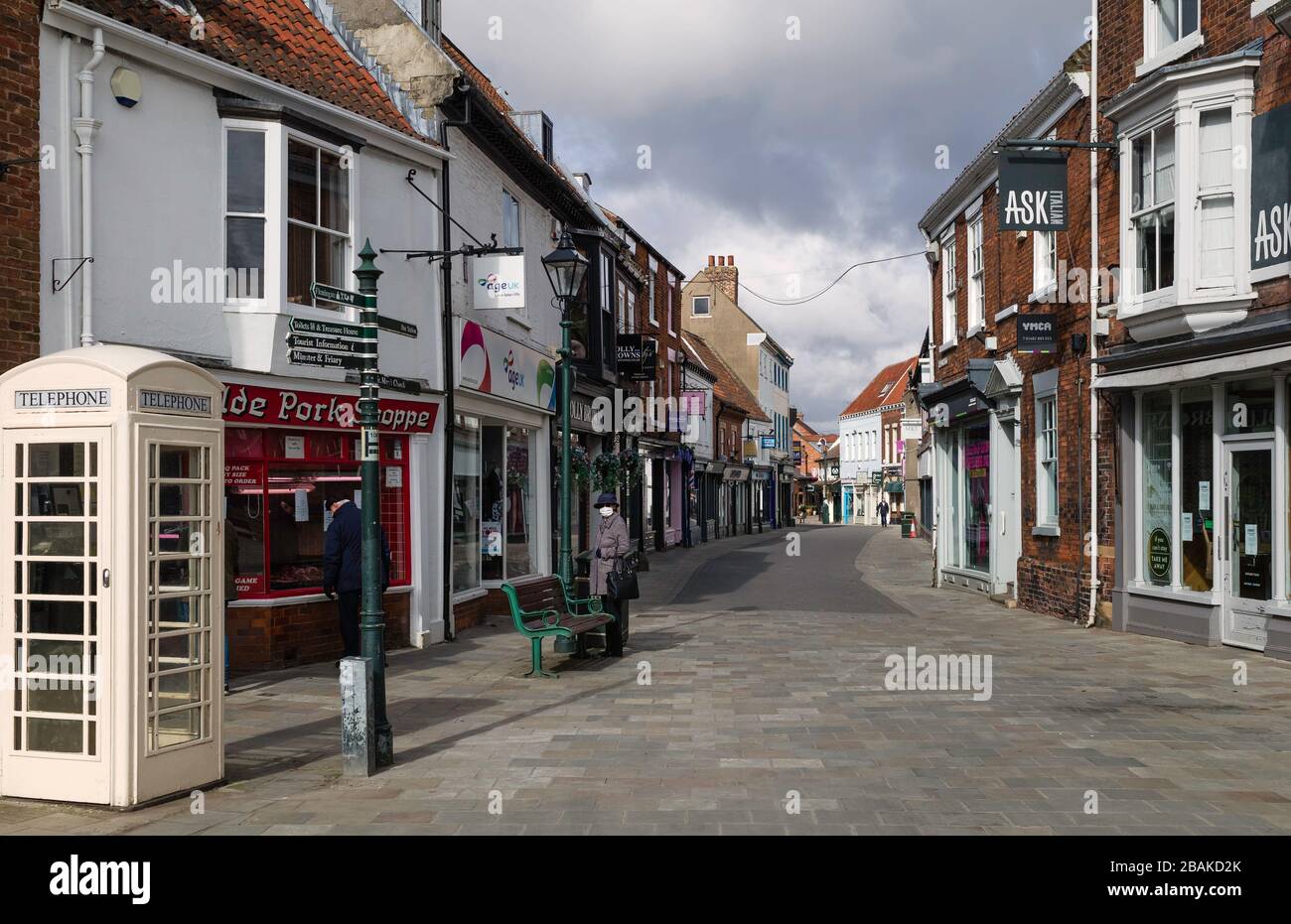 Businesses and shops closed and three pedestrians. one wearing protective face mask following Corona virus shut-down in Beverley, Yorkshire, UK. Stock Photo
