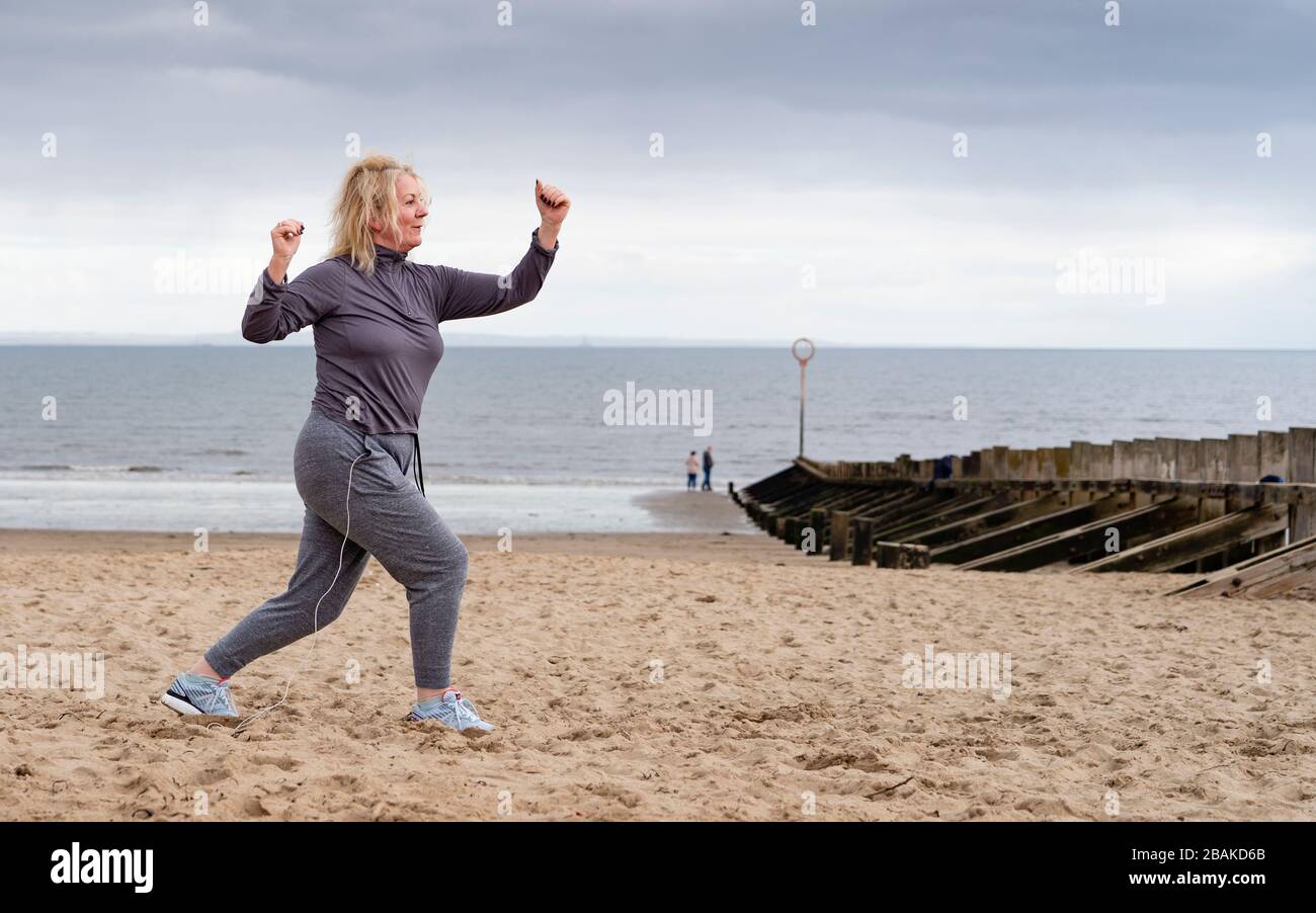 Portobello, Scotland, UK. 28 March, 2020. On the first weekend of the coronavirus lockdown the public were outdoors exercising and maintaining social distancing along Portobello beachfront promenade. Pictured; Annabel Meikle from Portobello working out on her special covid-19  solo training program set by her personal trainer. Iain Masterton/Alamy Live News Stock Photo