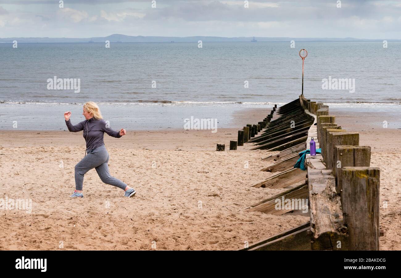 Portobello, Scotland, UK. 28 March, 2020. On the first weekend of the coronavirus lockdown the public were outdoors exercising and maintaining social distancing along Portobello beachfront promenade. Pictured; Annabel Meikle from Portobello working out on her special covid-19  solo training program set by her personal trainer. Iain Masterton/Alamy Live News Stock Photo