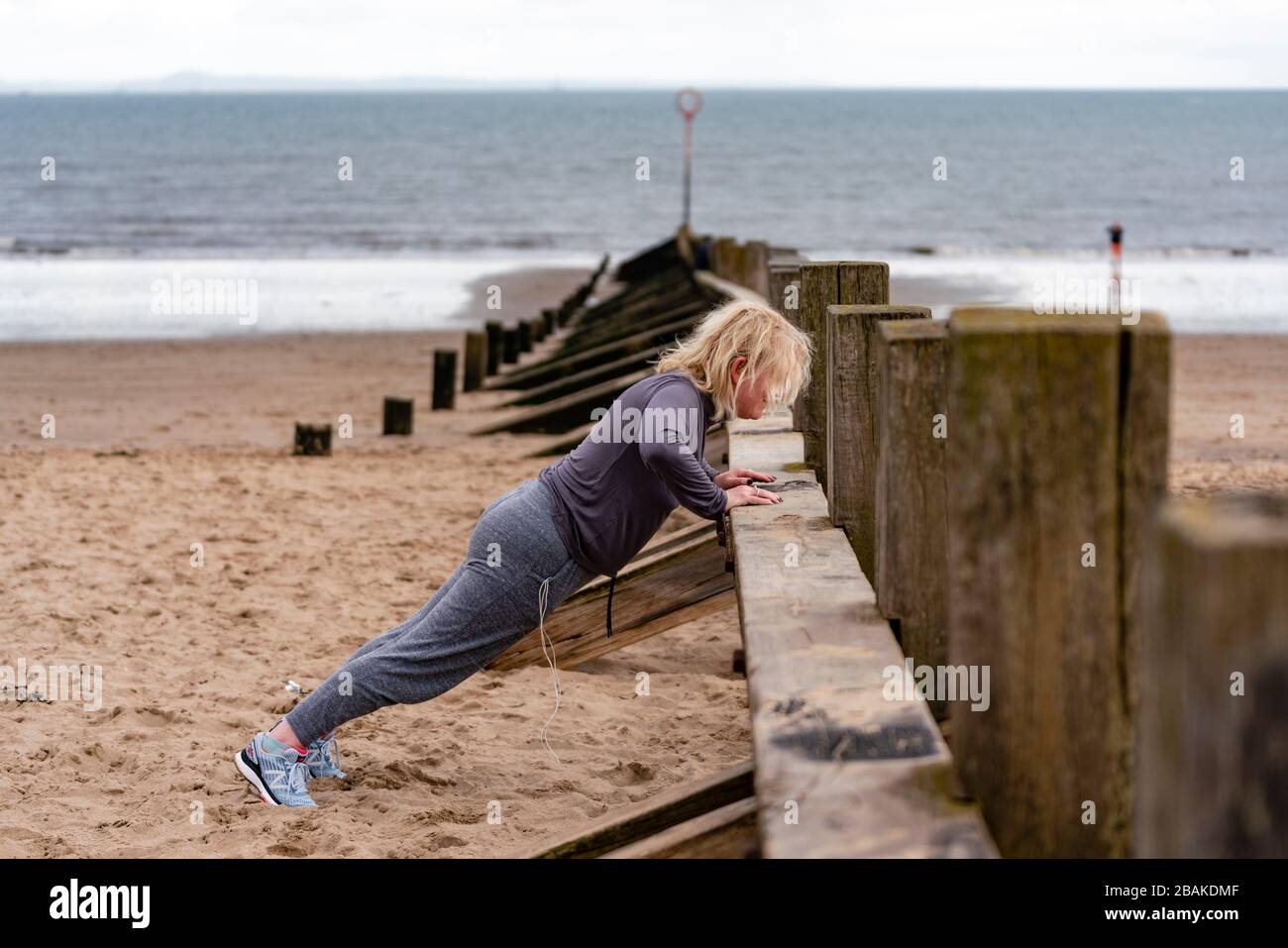 Portobello, Scotland, UK. 28 March, 2020. On the first weekend of the coronavirus lockdown the public were outdoors exercising and maintaining social distancing along Portobello beachfront promenade. Pictured; Annabel Meikle from Portobello working out on her special covid-19  solo training program set by her personal trainer. Iain Masterton/Alamy Live News Stock Photo