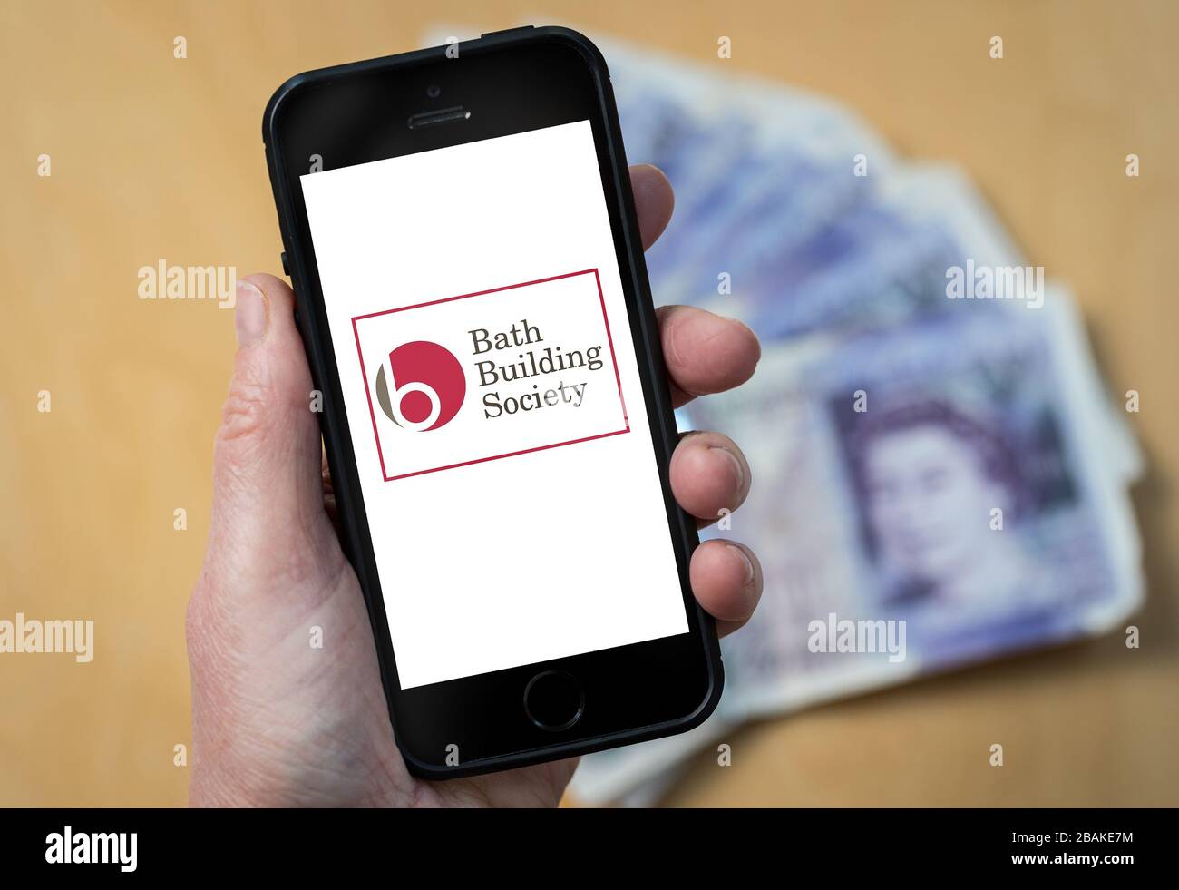 A woman holding a mobile phone showing Bath Building Society (editorial use only) Stock Photo
